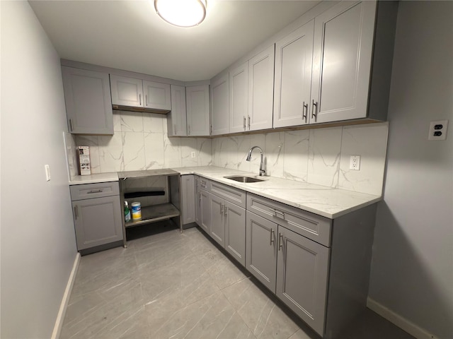 kitchen with gray cabinetry, baseboards, and a sink
