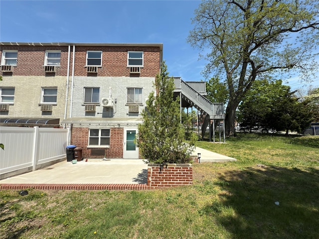 back of house with a lawn, brick siding, fence, and a patio area
