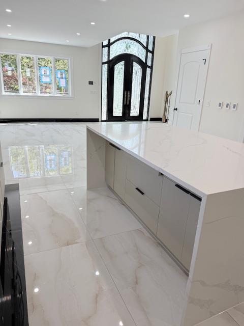kitchen featuring light stone countertops, marble finish floor, recessed lighting, a spacious island, and modern cabinets