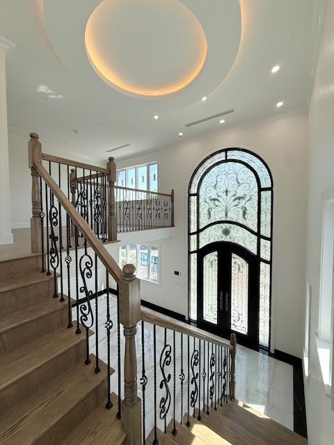 stairs featuring baseboards, a high ceiling, a tray ceiling, and recessed lighting