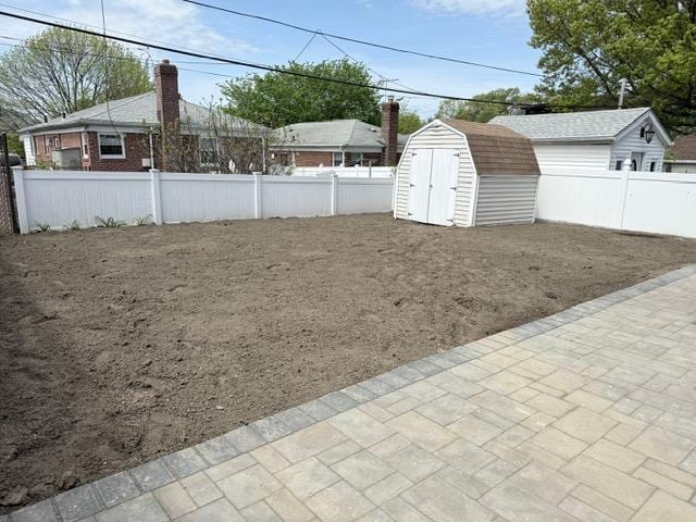 view of yard featuring a fenced backyard, an outbuilding, a patio area, and a shed