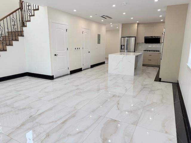 kitchen featuring stainless steel fridge, gray cabinets, a center island, cooktop, and modern cabinets