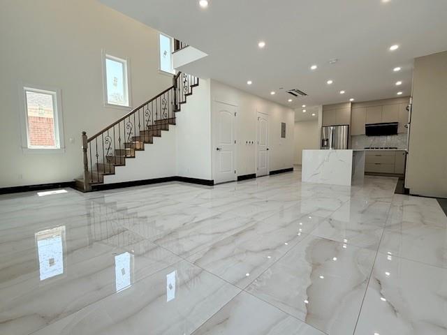 unfurnished living room with marble finish floor, recessed lighting, baseboards, visible vents, and stairway
