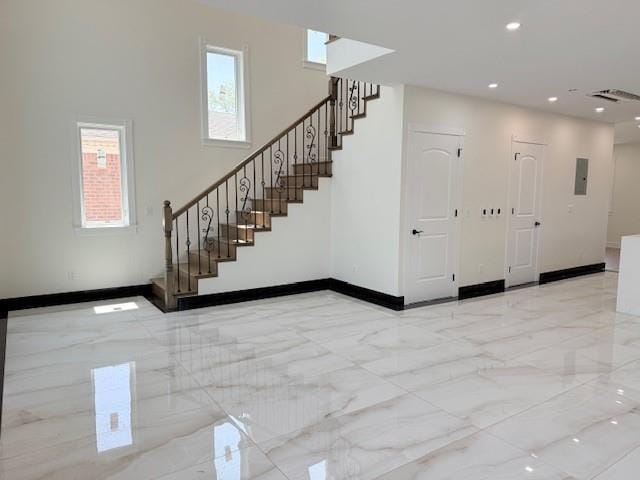 interior space featuring stairway, a healthy amount of sunlight, baseboards, and marble finish floor