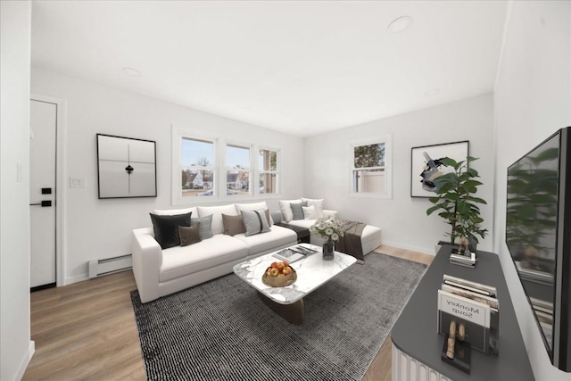 living room with baseboard heating, light wood-style floors, and baseboards