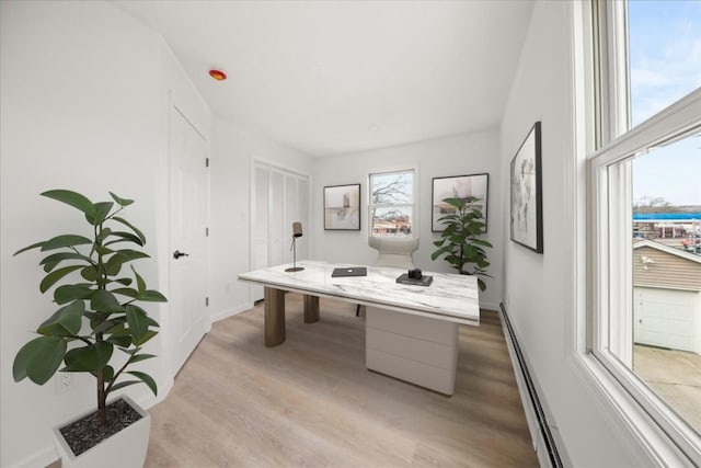 office area featuring light wood-style floors, a baseboard heating unit, and baseboards