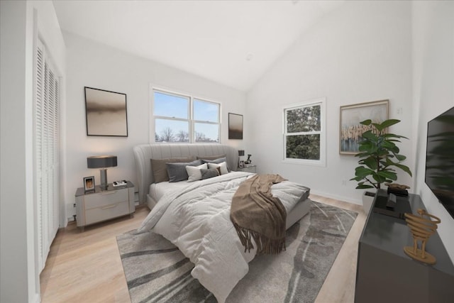 bedroom with light wood-style floors and high vaulted ceiling