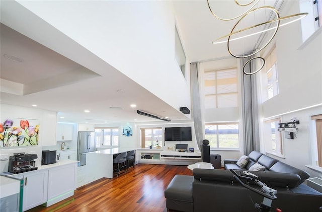 living room with a high ceiling, recessed lighting, and wood finished floors