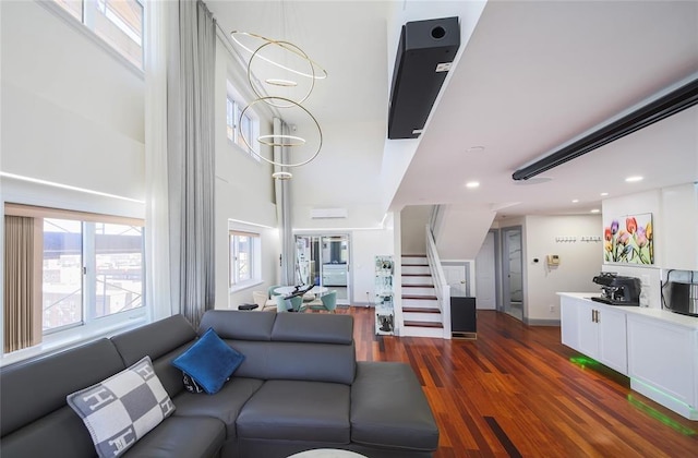 living area with recessed lighting, a high ceiling, stairs, and wood finished floors