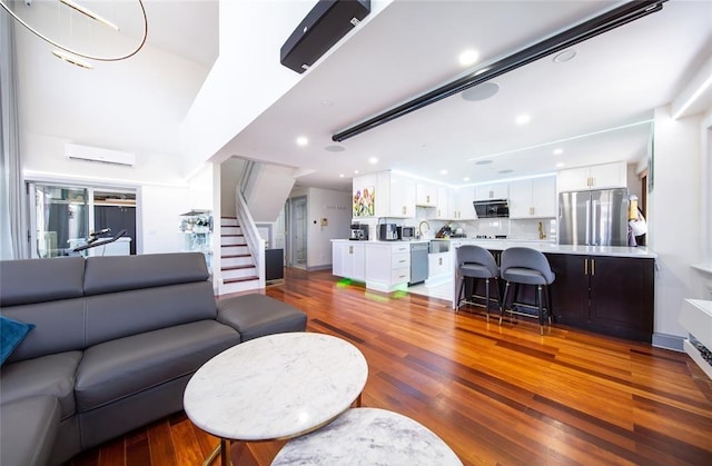 living room featuring recessed lighting, a wall mounted AC, stairs, and wood finished floors