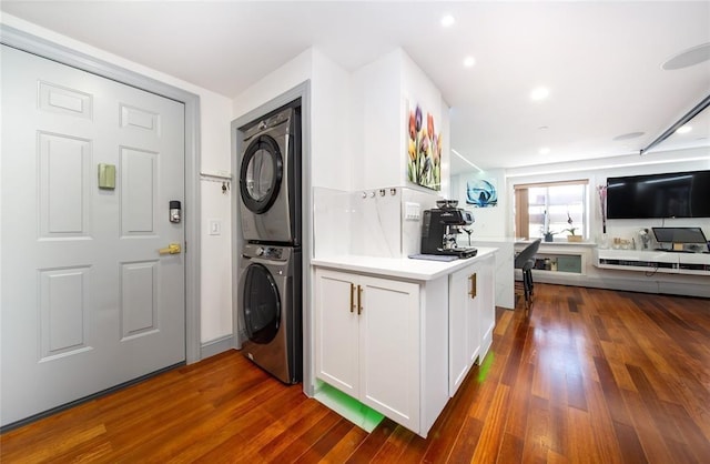 washroom with stacked washing maching and dryer, recessed lighting, and dark wood finished floors