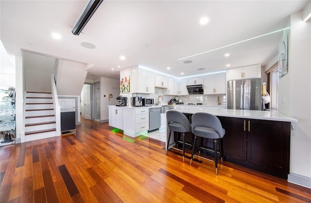 kitchen with light countertops, appliances with stainless steel finishes, white cabinets, and a peninsula