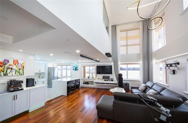 living room featuring recessed lighting, dark wood finished floors, and a high ceiling