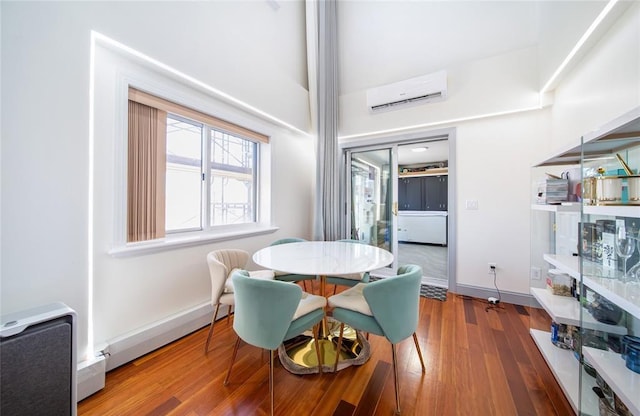 dining space featuring baseboards, a wall mounted AC, and wood finished floors