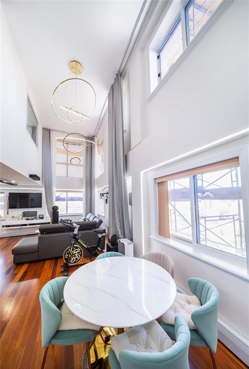 dining area with a wealth of natural light, wood finished floors, and a towering ceiling