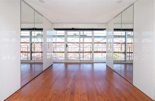 unfurnished room with floor to ceiling windows and wood finished floors