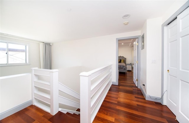 corridor featuring wood finished floors and an upstairs landing