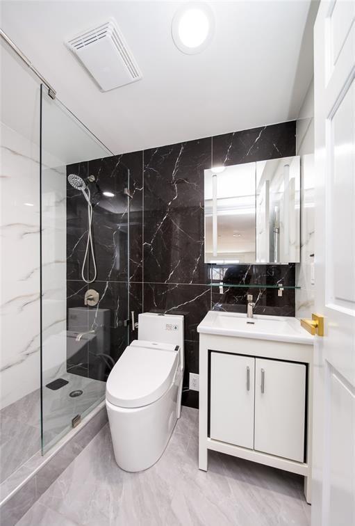 bathroom with visible vents, tile walls, vanity, toilet, and a marble finish shower