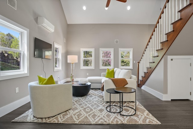 living area with an AC wall unit, high vaulted ceiling, plenty of natural light, and stairway