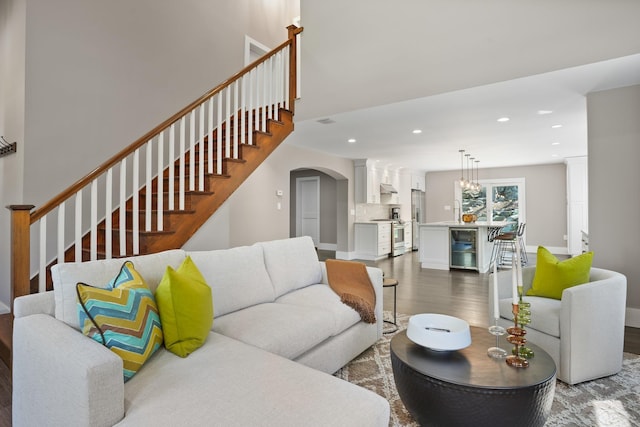 living room featuring stairs, wine cooler, dark wood-style floors, recessed lighting, and arched walkways