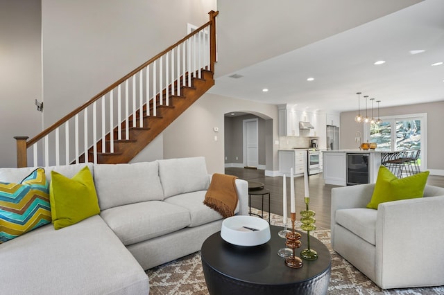 living room featuring arched walkways, stairs, baseboards, wine cooler, and recessed lighting
