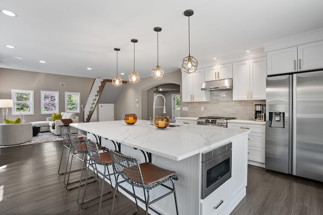 kitchen with a breakfast bar area, dark wood-style flooring, appliances with stainless steel finishes, a sink, and under cabinet range hood