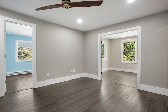 spare room featuring dark wood-style flooring, ceiling fan, a wealth of natural light, and baseboard heating