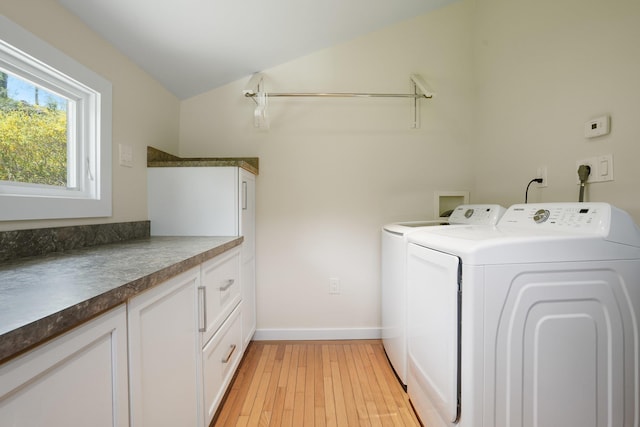 clothes washing area featuring baseboards, washing machine and dryer, light wood-type flooring, and cabinet space