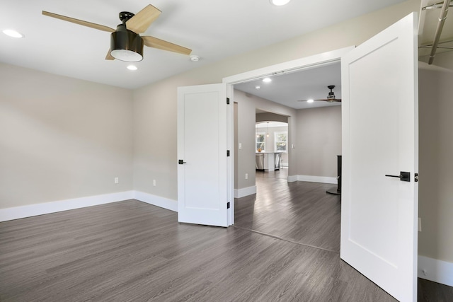 empty room featuring dark wood-type flooring, a ceiling fan, arched walkways, and recessed lighting