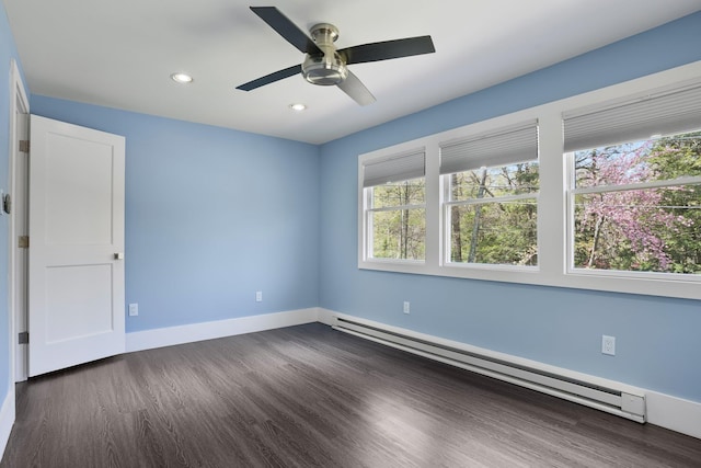 spare room with dark wood finished floors, baseboard heating, and a wealth of natural light