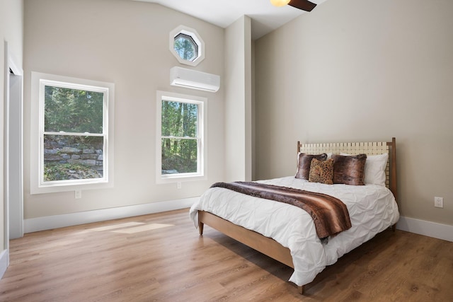 bedroom featuring a wall mounted AC, multiple windows, and wood finished floors