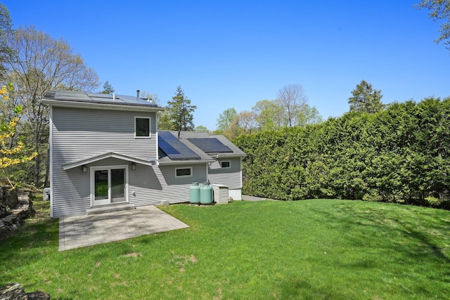 rear view of house with a lawn, a patio, and solar panels