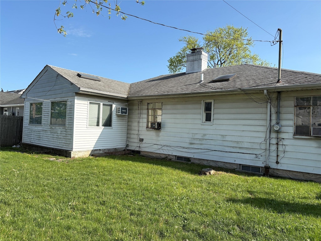 back of house with fence, a wall mounted air conditioner, a chimney, cooling unit, and a lawn