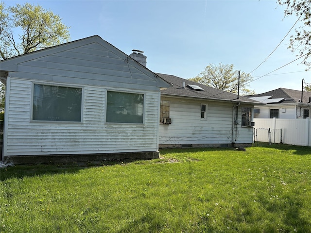 back of property with fence, a yard, and a chimney