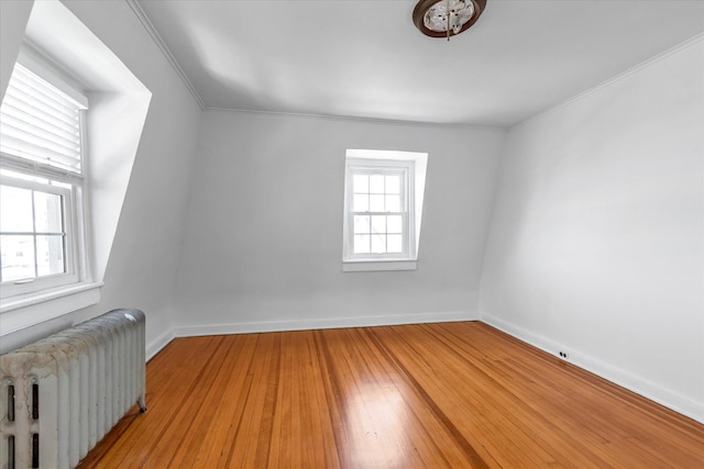 additional living space featuring wood-type flooring, baseboards, and radiator