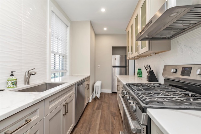 kitchen with tasteful backsplash, a sink, radiator, stainless steel appliances, and wall chimney exhaust hood