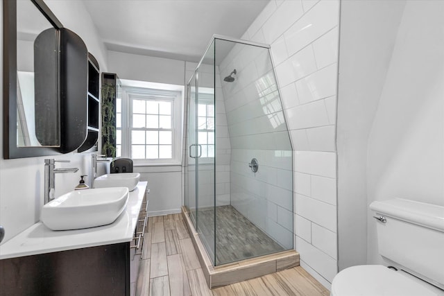 bathroom with toilet, a shower stall, wood finished floors, and vanity