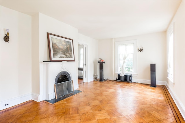 unfurnished living room with baseboards, radiator, and a fireplace
