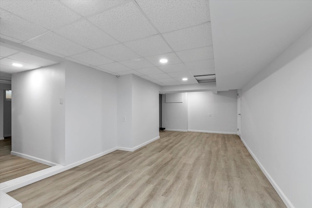 finished below grade area featuring recessed lighting, baseboards, light wood-style flooring, and a drop ceiling