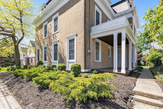 view of side of property featuring stucco siding and covered porch