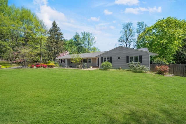 rear view of house featuring fence and a yard