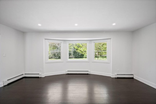 unfurnished room with a healthy amount of sunlight, baseboard heating, a baseboard heating unit, and wood finished floors