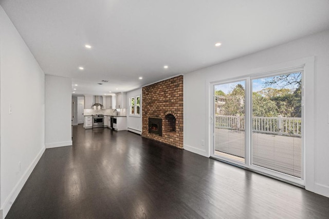 unfurnished living room with recessed lighting, dark wood finished floors, baseboards, and a fireplace