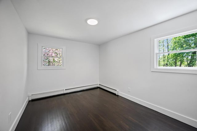 spare room featuring baseboard heating, baseboards, dark wood-style floors, and a healthy amount of sunlight
