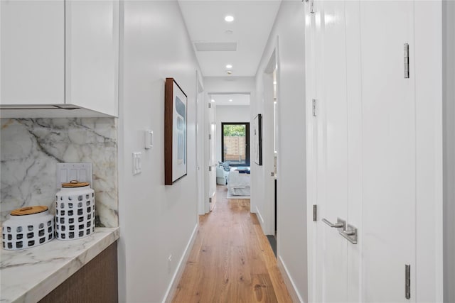 corridor featuring baseboards, recessed lighting, and light wood finished floors
