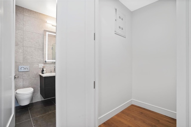 bathroom with vanity, baseboards, toilet, and tile walls