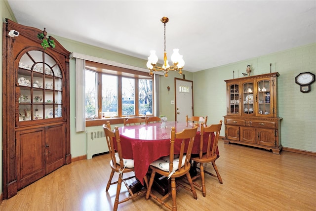 dining area with baseboards, an inviting chandelier, radiator heating unit, and light wood-type flooring