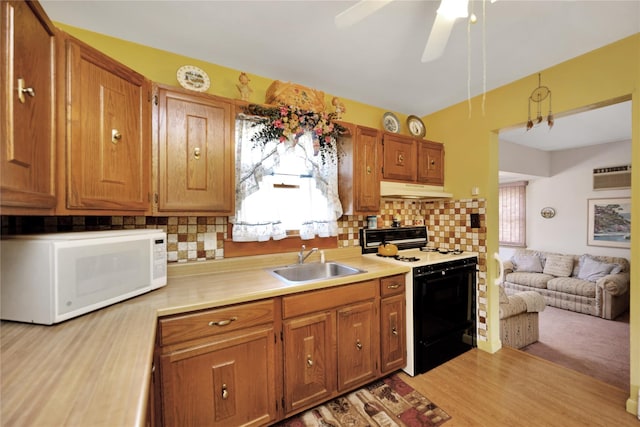 kitchen featuring white microwave, light countertops, under cabinet range hood, a sink, and range