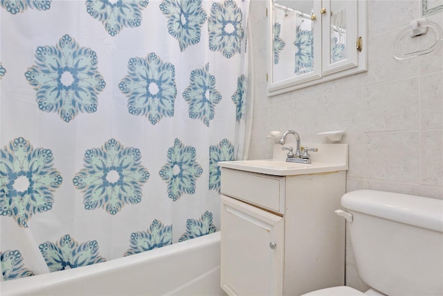 bathroom with tile walls, vanity, toilet, and shower / tub combo