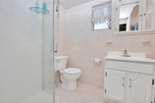 full bath with vanity, toilet, tile walls, tile patterned floors, and a stall shower
